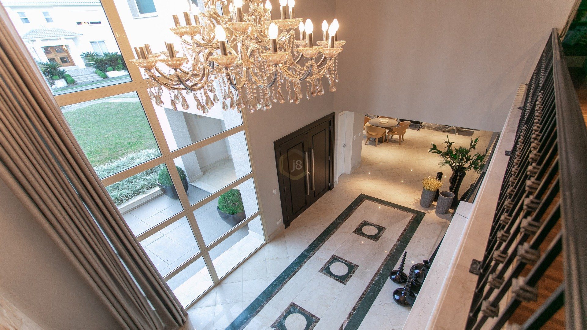 Foto de cima para baixo com entrada de casa formada por porta e lustre imponentes