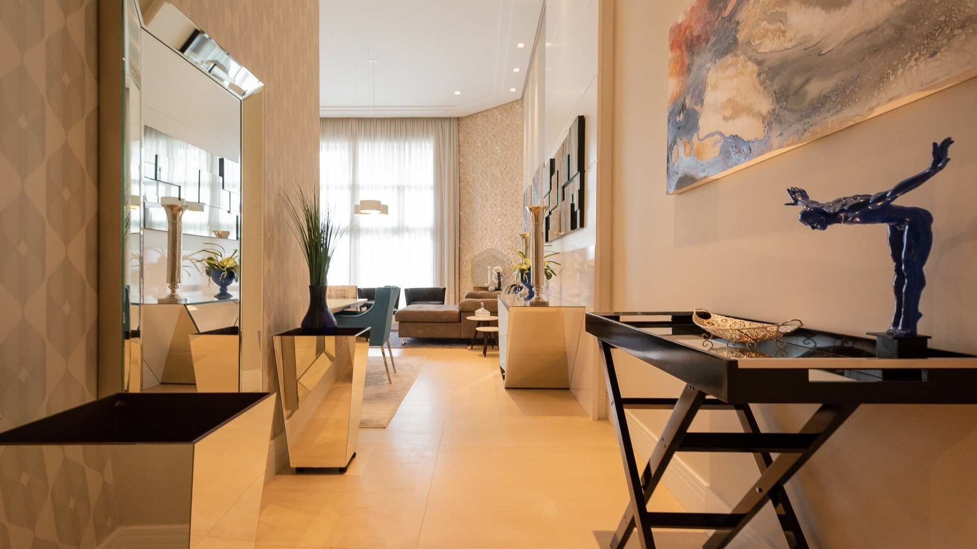 Entrada de casa formada por corredor com plantas, mesa e decorado com quadros