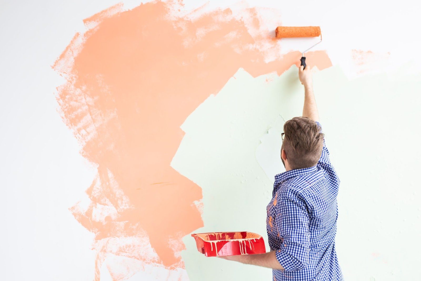 homem pintando parede branca de laranja