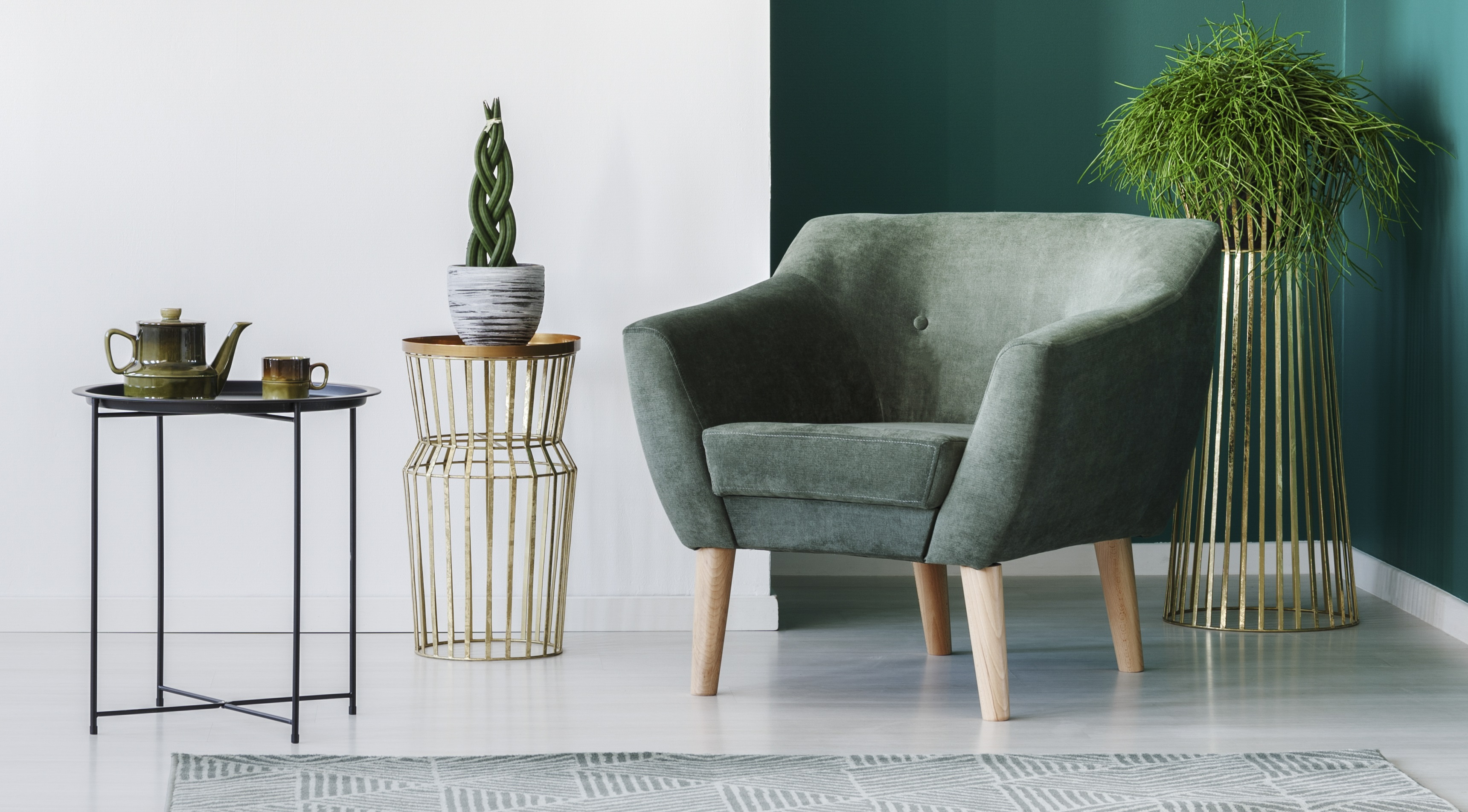 sala minimalista com parede e poltrona verdes, mesas de apoio e folhagem